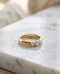 Three stone gold ring on wet marble