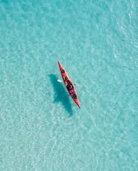 Red kayak paddling on turquoise water