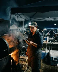 Pitmaster checking barbecue temperature at night